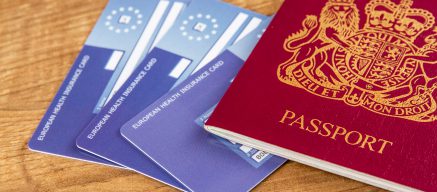 Passport and health insurance cards lying on wooden table