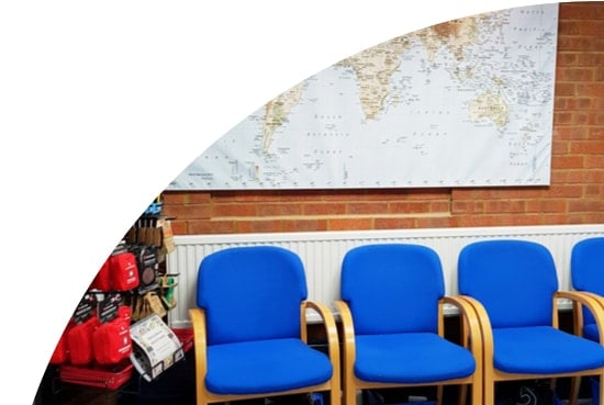 Waiting area in the reception of Hitchin travel clinic with blue chairs, a wall map, travel health kits and accessories