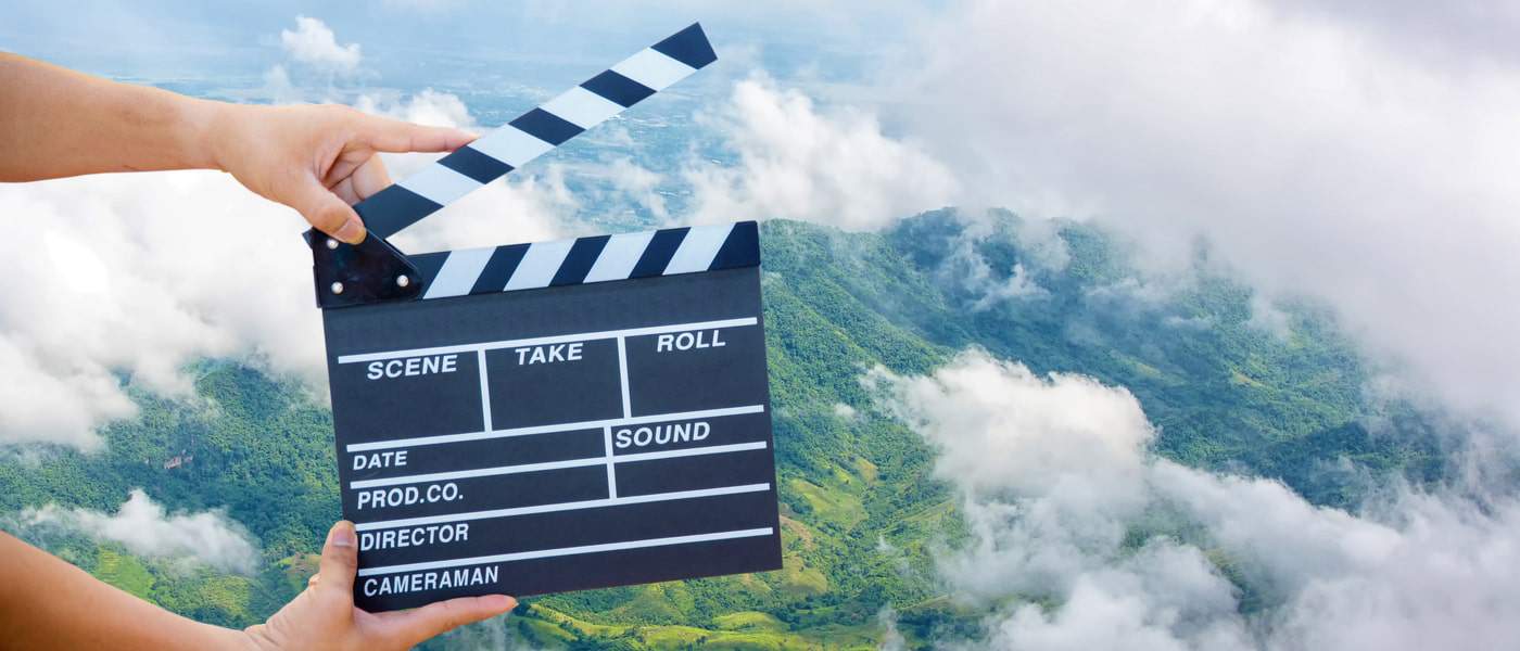 Clapperboard in front of cloudy mountains