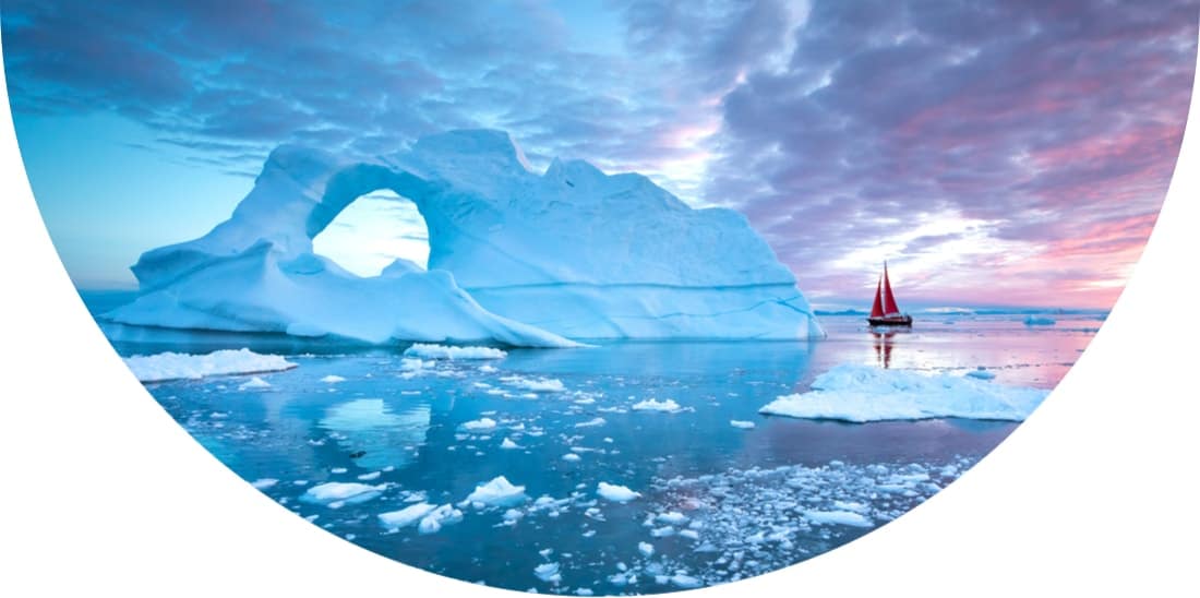 Little red boat sailing between icebergs in Disko Bay glacier during midnight sun season, Ilulissat, Greenland