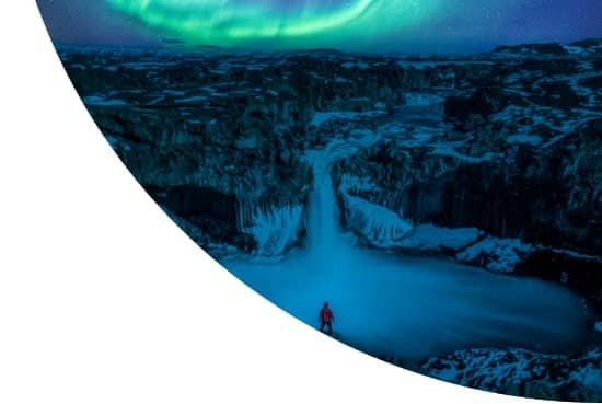 Man stands watching Aurora Borealis Northern Lights at Aldeyjarfoss waterfall in Iceland, Europe.