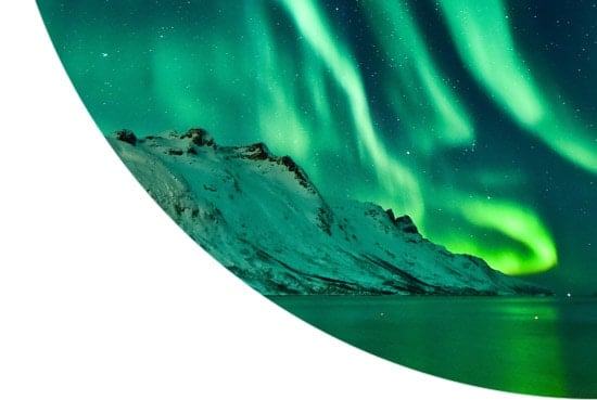 Aurora Borealis above snowy mountains in Norway