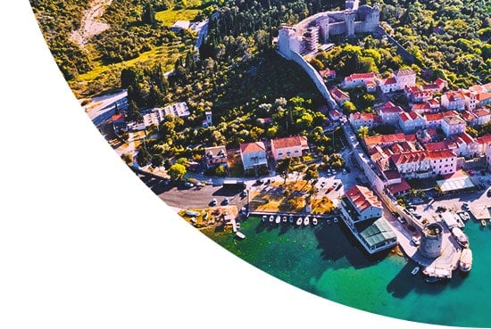 Aerial view of houses and trees by a lake in Europe