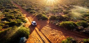 4x4 driving down a red dirt track path in Shark Bay, Australia, at sunset
