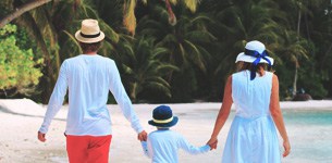 Two adults and a child holding hands on a sandy beach